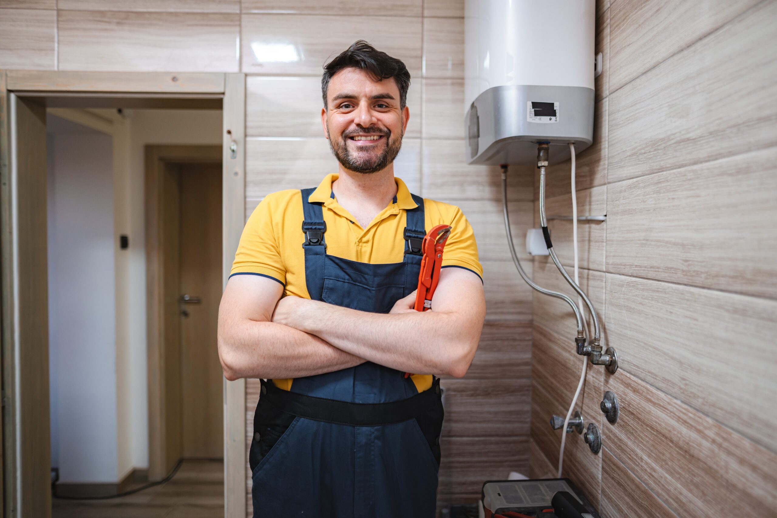 Portrait,Of,Smiling,Plumber,Holding,Pipe,Wrench,In,Bathroom